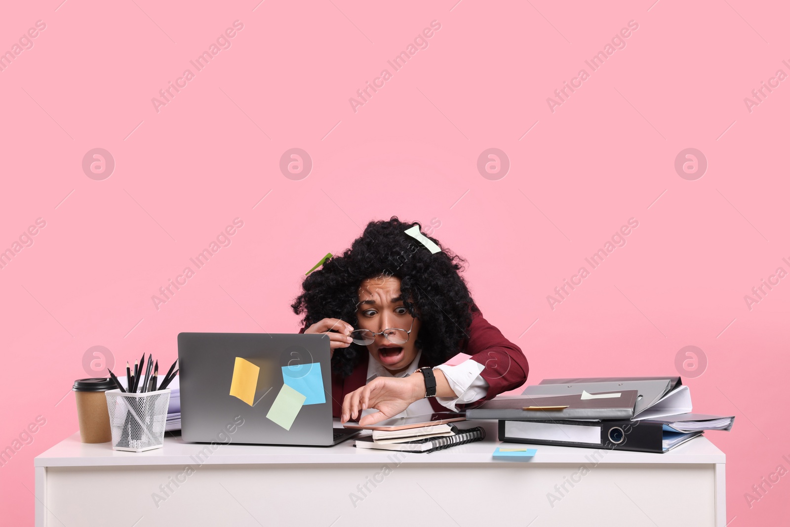 Photo of Stressful deadline. Scared woman checking time on wristwatch at white desk against pink background. Sticky notes everywhere as reminders