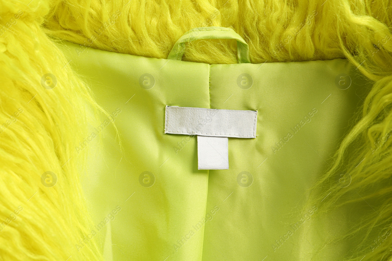 Photo of Blank clothing label on light green jacket, top view