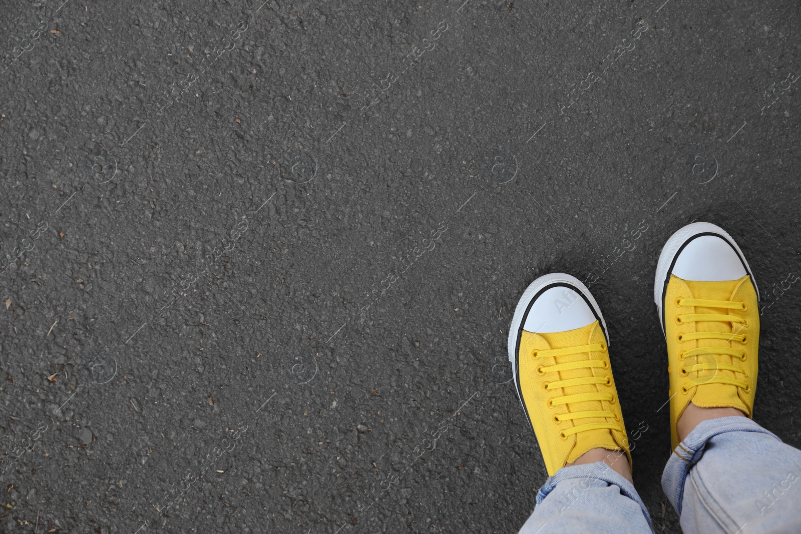 Photo of Woman standing on asphalt, top view. Space for text