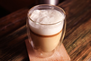 Photo of Glass with delicious latte on wooden table