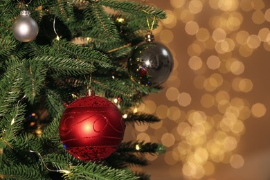 Beautiful baubles hanging on Christmas tree against blurred festive lights, closeup. Space for text