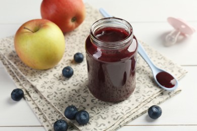 Photo of Tasty baby food in jar, blueberries and apples on white table