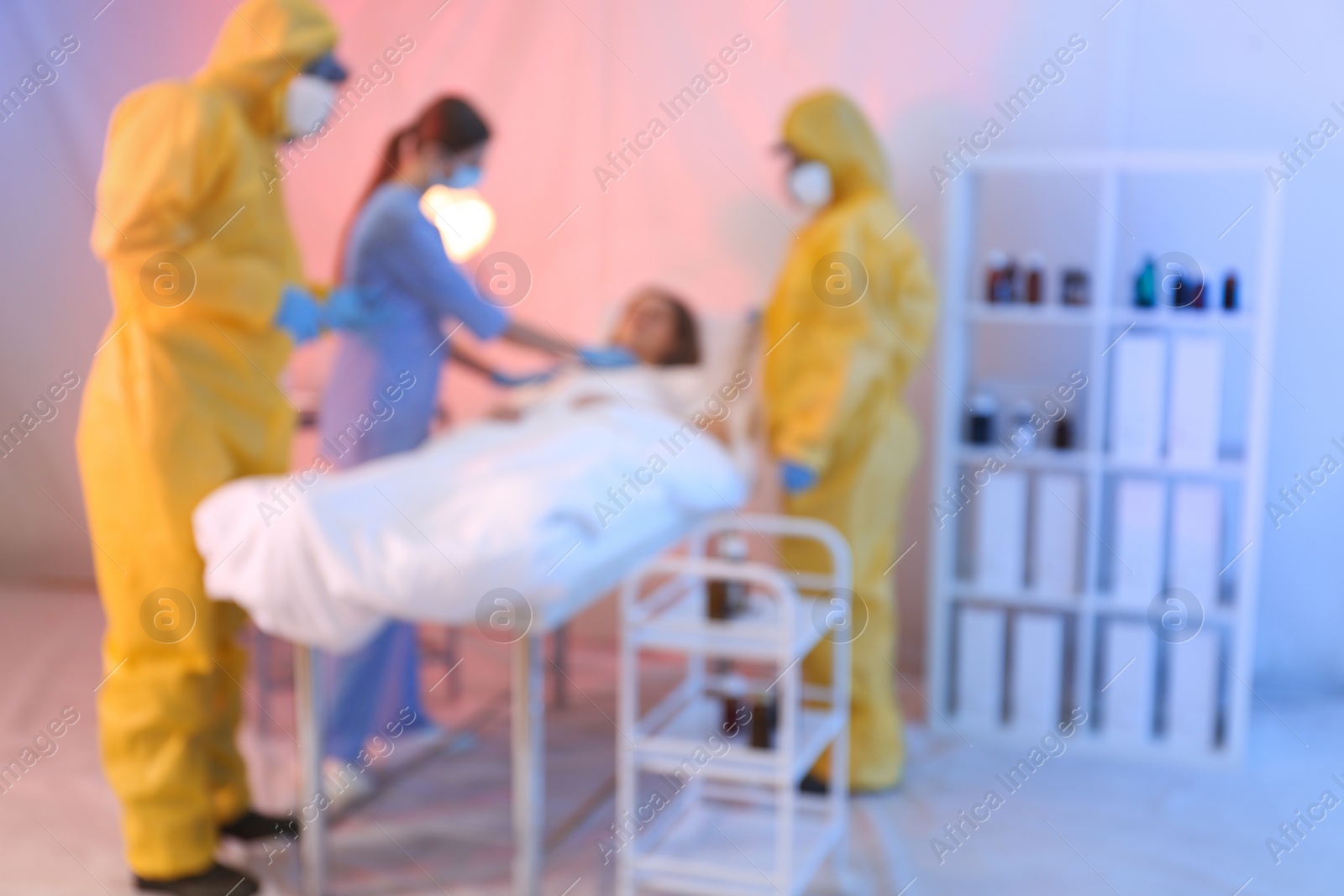 Photo of Blurred view of professional paramedics examining patient with virus in quarantine ward