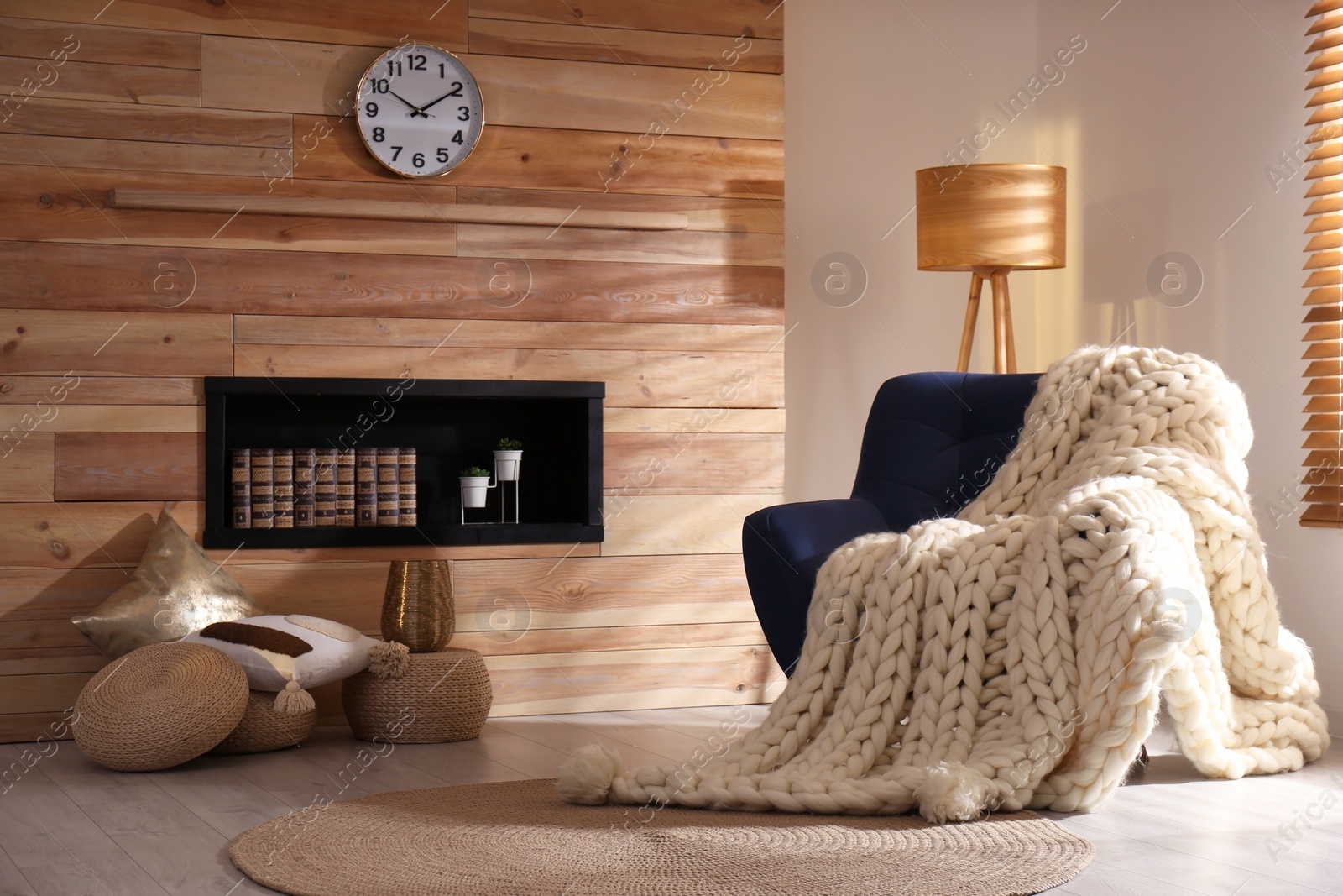 Photo of Soft knitted blanket on armchair in living room. Interior element