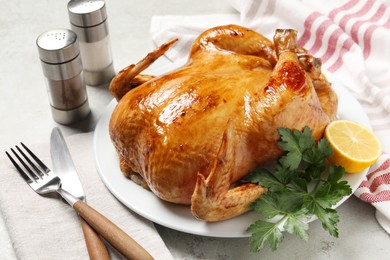 Photo of Tasty roasted chicken with parsley and lemon served on light grey table