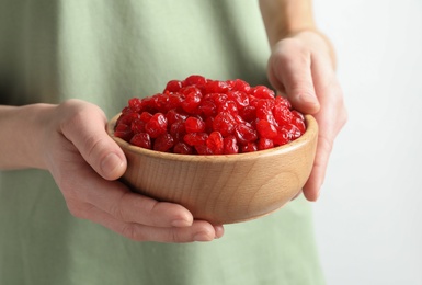 Photo of Woman holding bowl with tasty cherries on light background, closeup. Dried fruits as healthy food