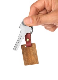 Woman holding key with wooden keychain on white background, closeup