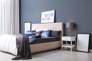 Photo of Comfortable bed with pillows and soft blanket in room. Stylish interior design