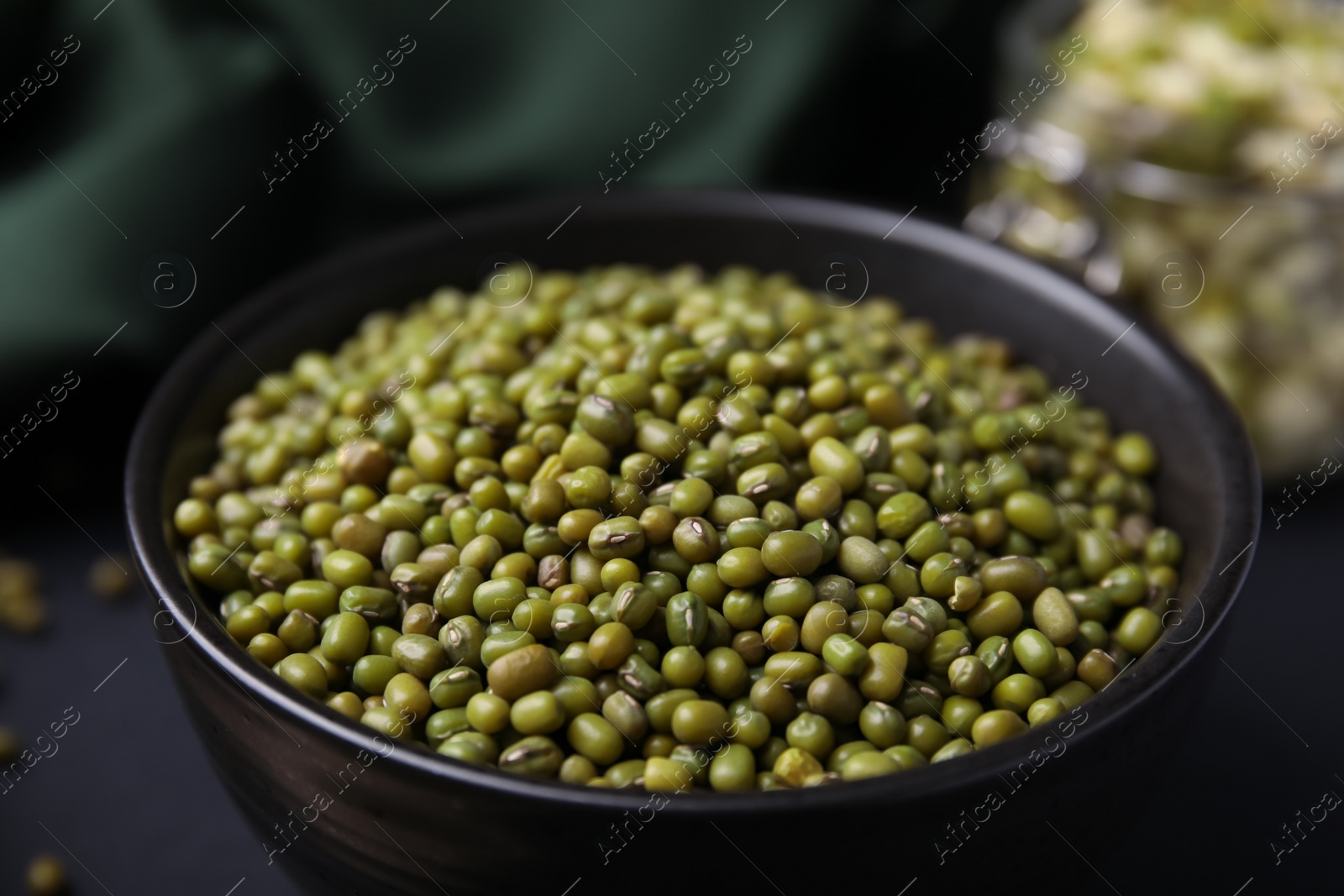 Photo of Bowl with green mung beans on black background, closeup