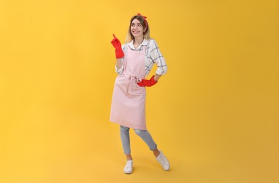 Photo of Young housewife in gloves on yellow background