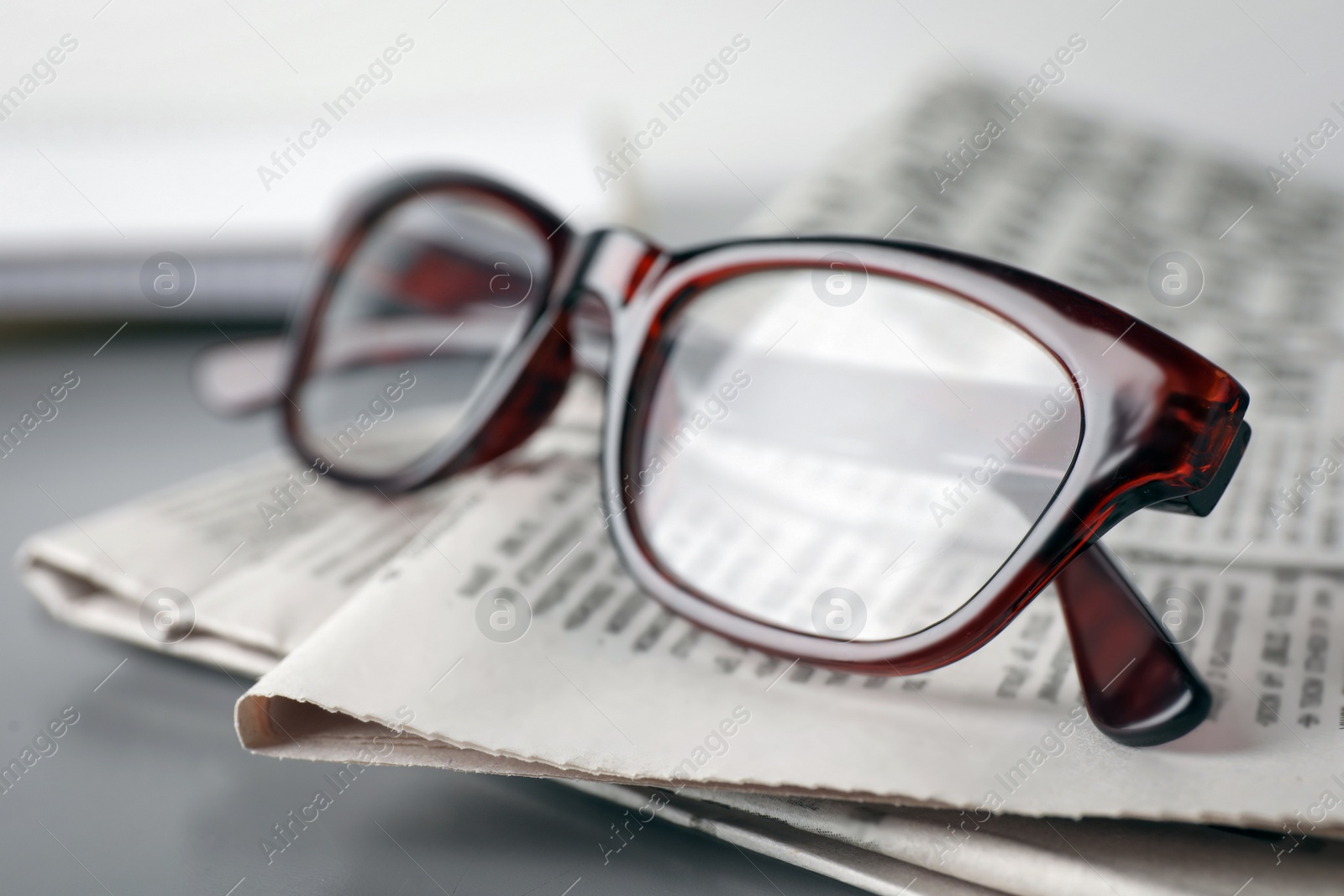 Photo of Newspapers and glasses on grey table, closeup