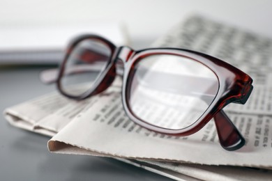 Newspapers and glasses on grey table, closeup