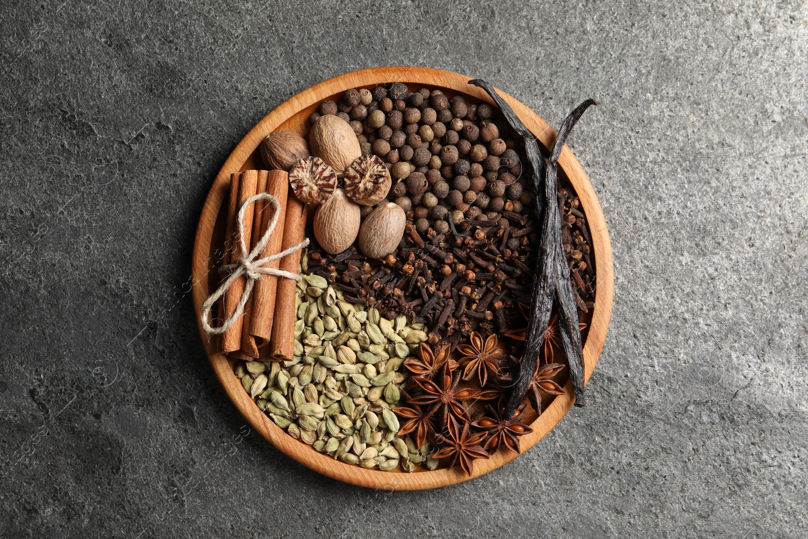 Photo of Different spices and nuts on gray textured table, top view