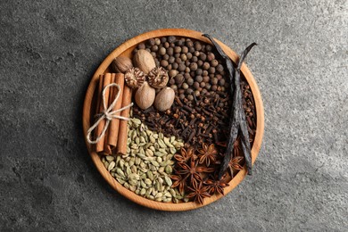 Photo of Different spices and nuts on gray textured table, top view