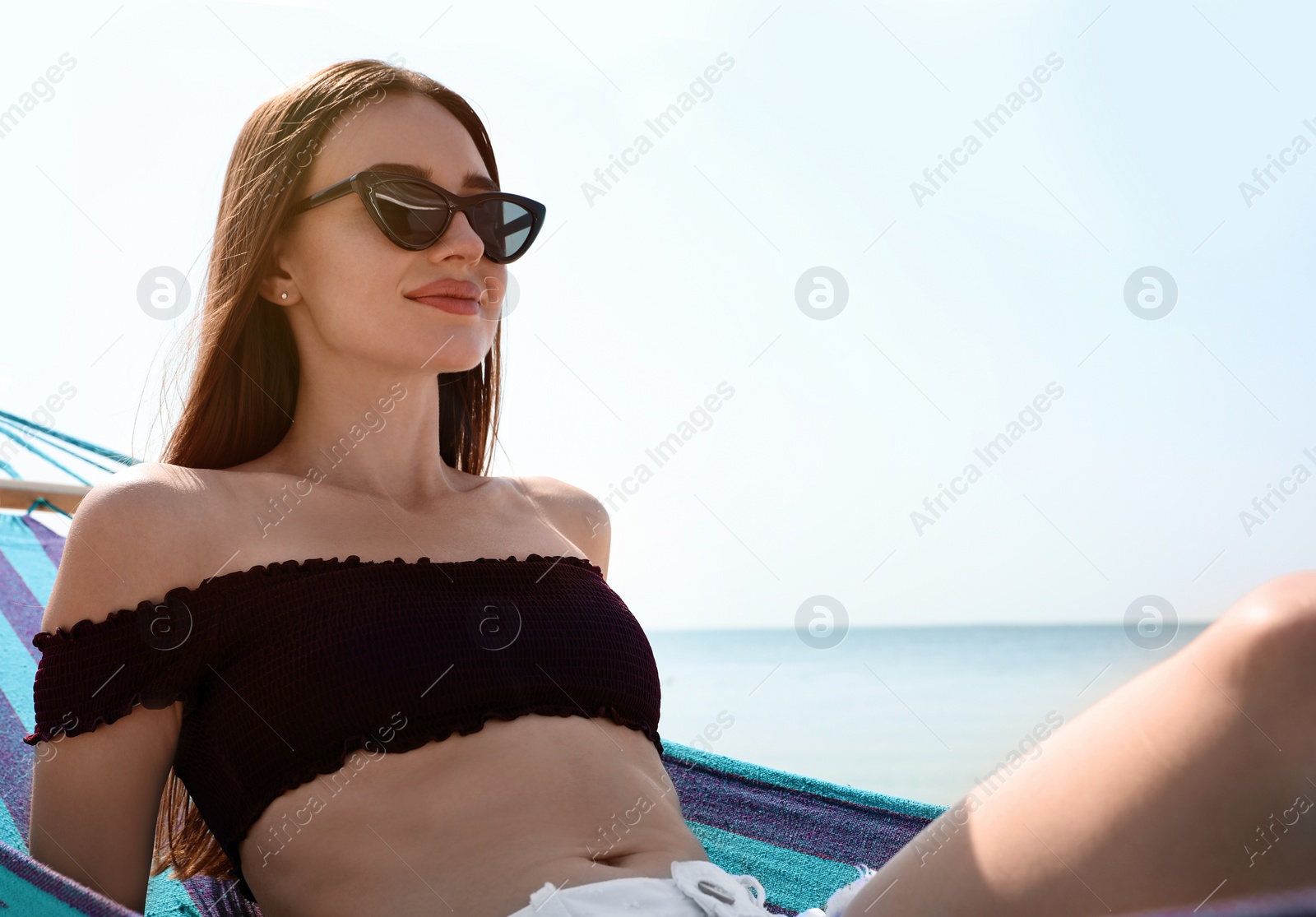 Photo of Young woman relaxing in hammock on beach