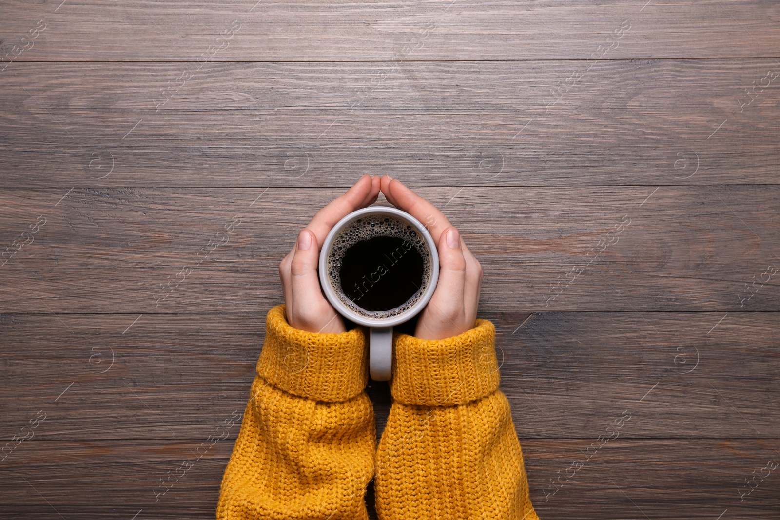 Photo of Woman with cup of coffee at wooden table, top view