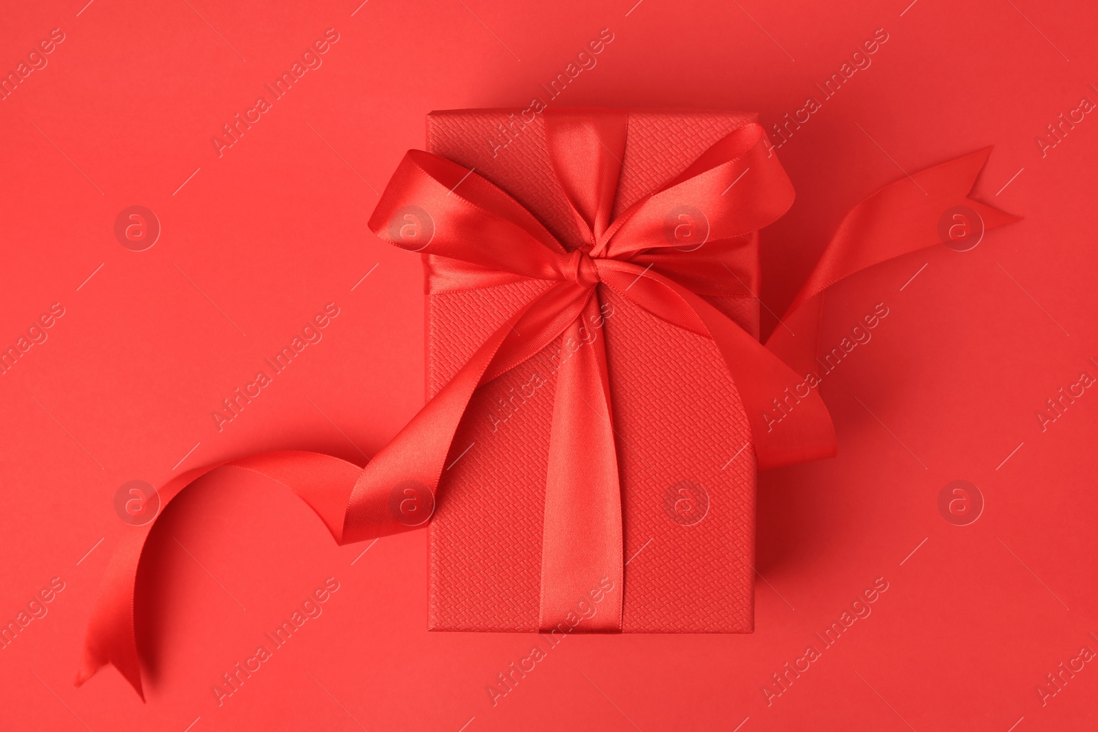 Photo of Beautiful gift box with bow on red background, top view