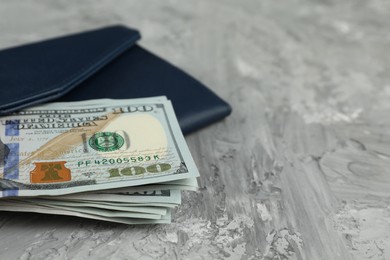 Photo of Money exchange. Wallet with dollar banknotes on grey stone background, closeup. Space for text