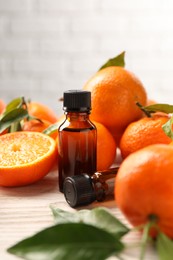 Photo of Bottles of tangerine essential oil and fresh fruits on wooden table