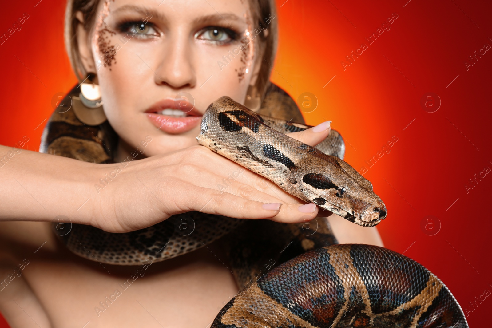 Photo of Beautiful woman with boa constrictor on bright colorful background, closeup