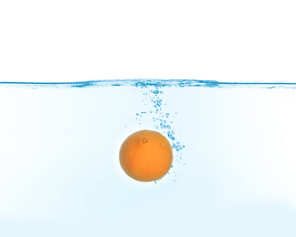 Photo of Ripe orange falling down into clear water against white background