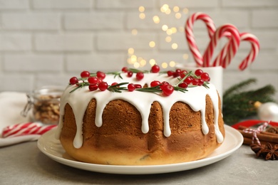 Traditional Christmas cake with cranberries, pomegranate seeds and rosemary on light grey table