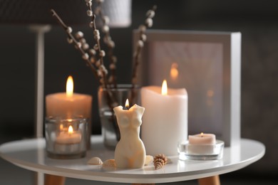 Beautiful body shaped candles and willow bouquet on table indoors