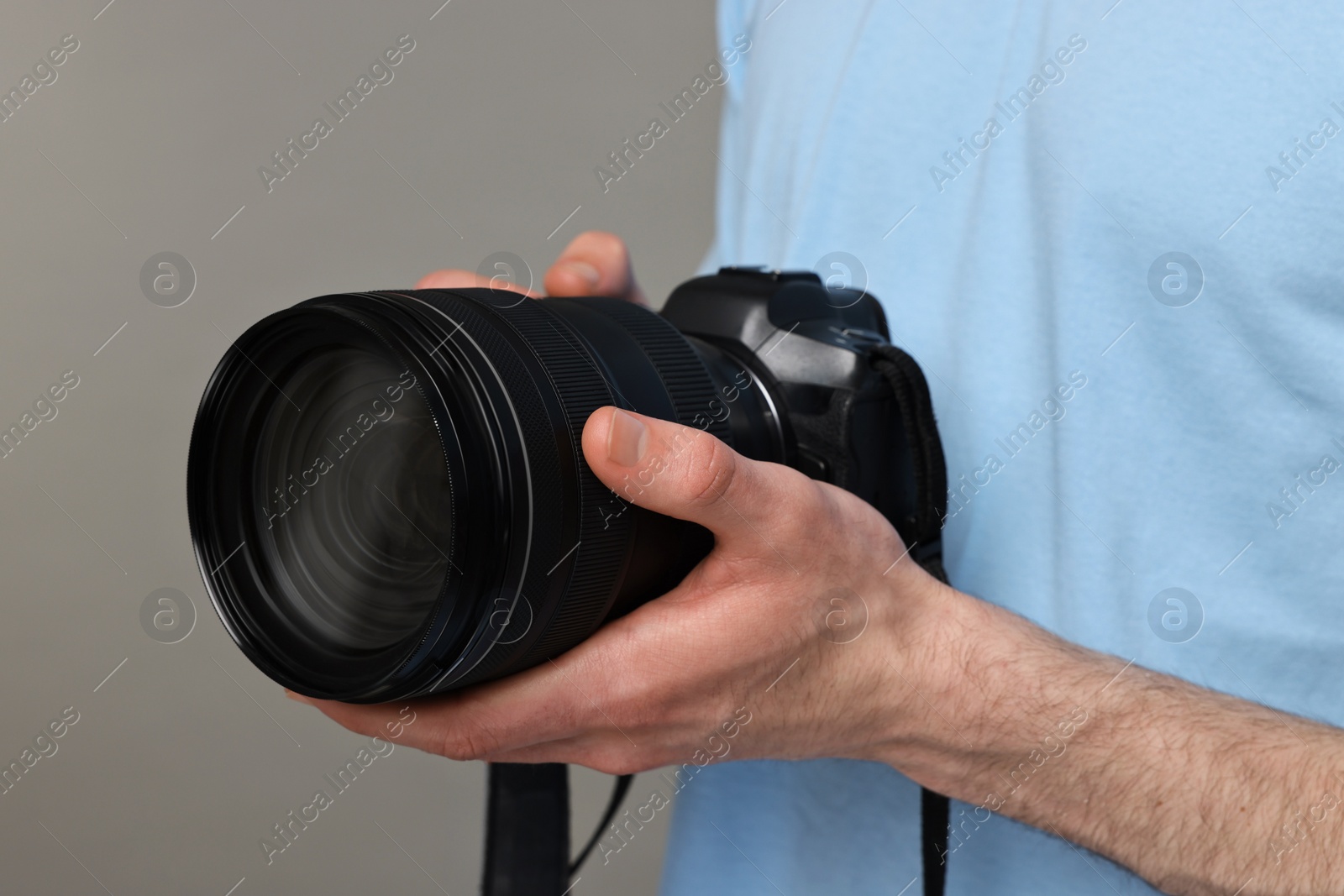 Photo of Photographer holding camera on grey background, closeup