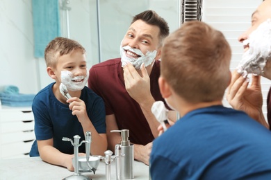 Photo of Dad and son with shaving foam at mirror