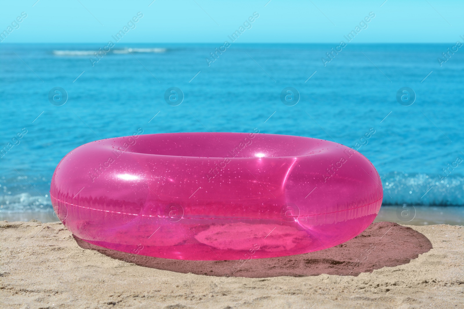 Photo of Bright inflatable ring on sandy beach near sea