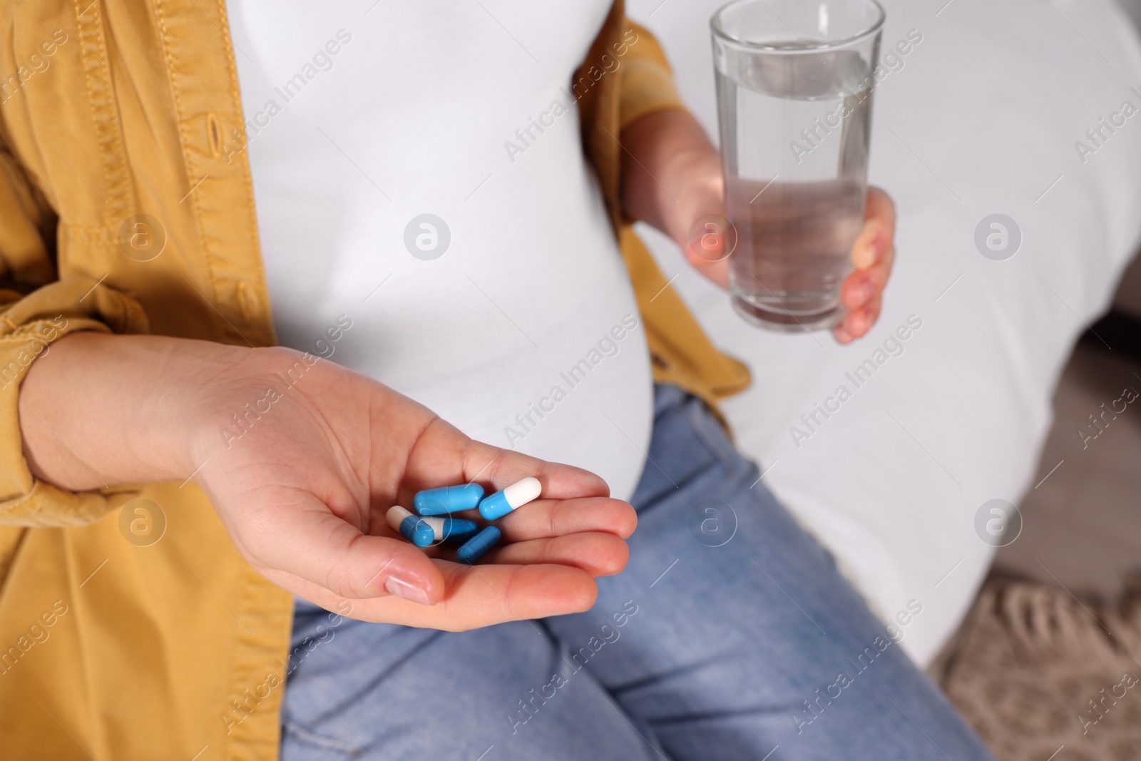 Photo of Pregnant woman taking pills on bed, closeup