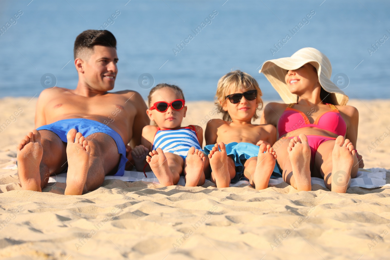 Photo of Happy family lying on sandy beach near sea. Summer holidays