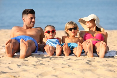 Photo of Happy family lying on sandy beach near sea. Summer holidays