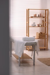 Photo of Comfortable massage table with clean towels in spa center