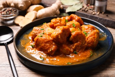 Photo of Plate of delicious chicken curry on wooden table, closeup