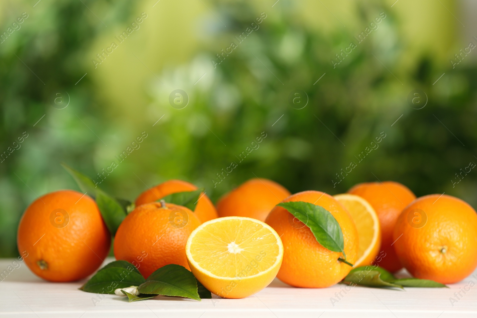 Photo of Fresh ripe oranges on white table against blurred background. Space for text