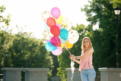 Photo of Young woman with colorful balloons outdoors on sunny day