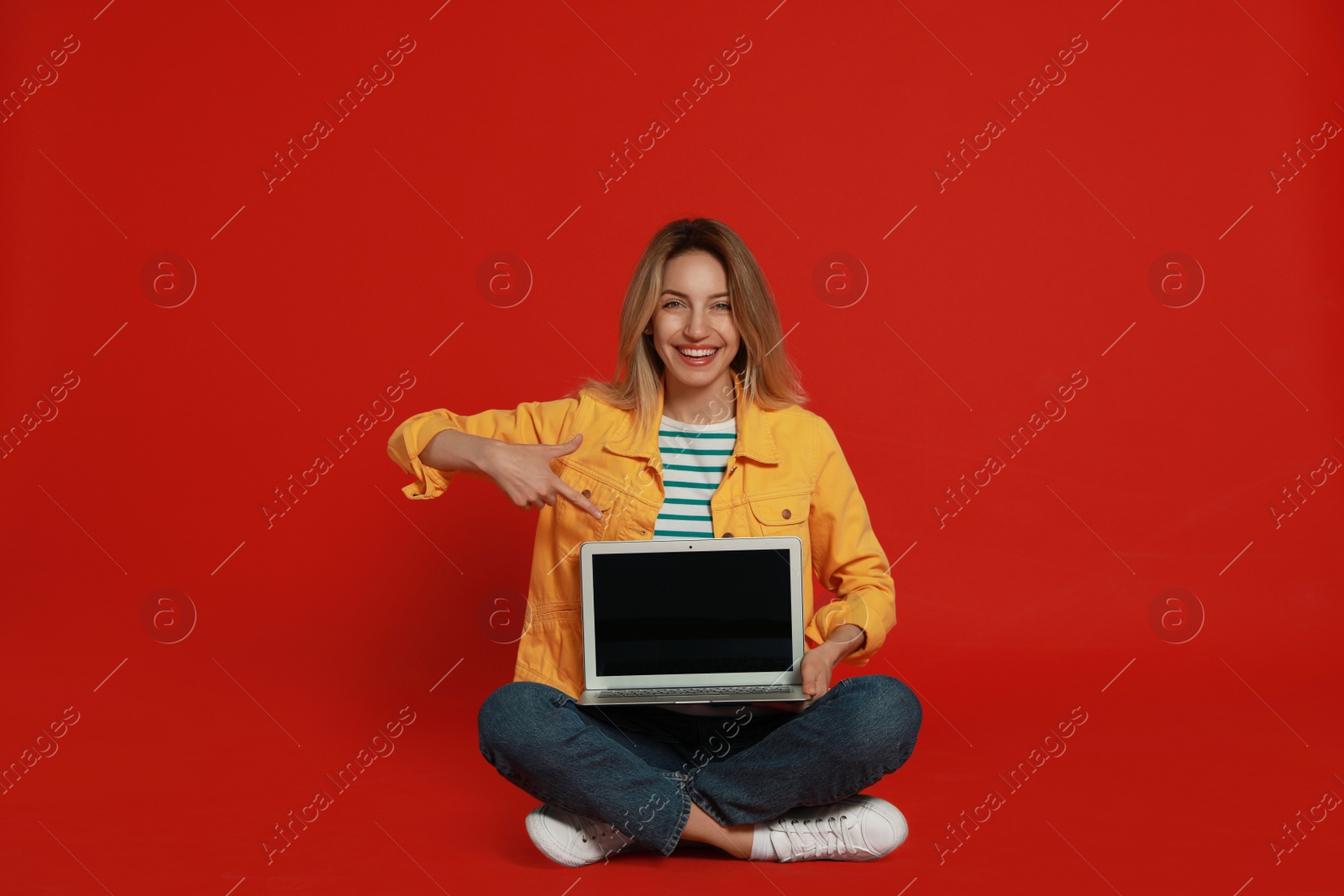 Photo of Young woman with modern laptop on red background