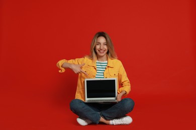 Young woman with modern laptop on red background