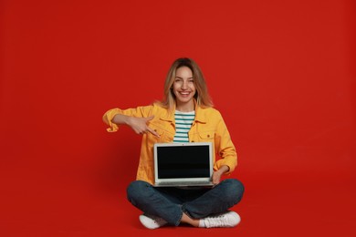 Photo of Young woman with modern laptop on red background