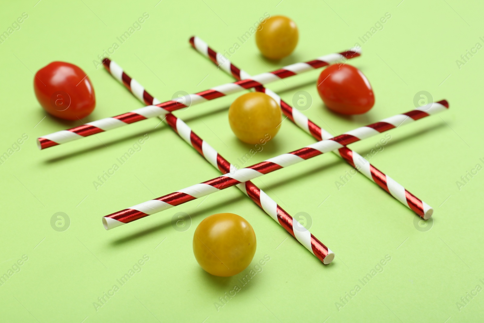 Photo of Tic tac toe game made with cherry tomatoes on light green background