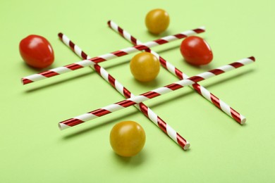 Tic tac toe game made with cherry tomatoes on light green background