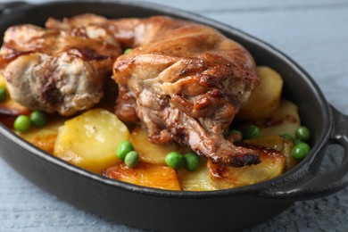 Photo of Tasty cooked rabbit with vegetables in baking dish on grey table, closeup