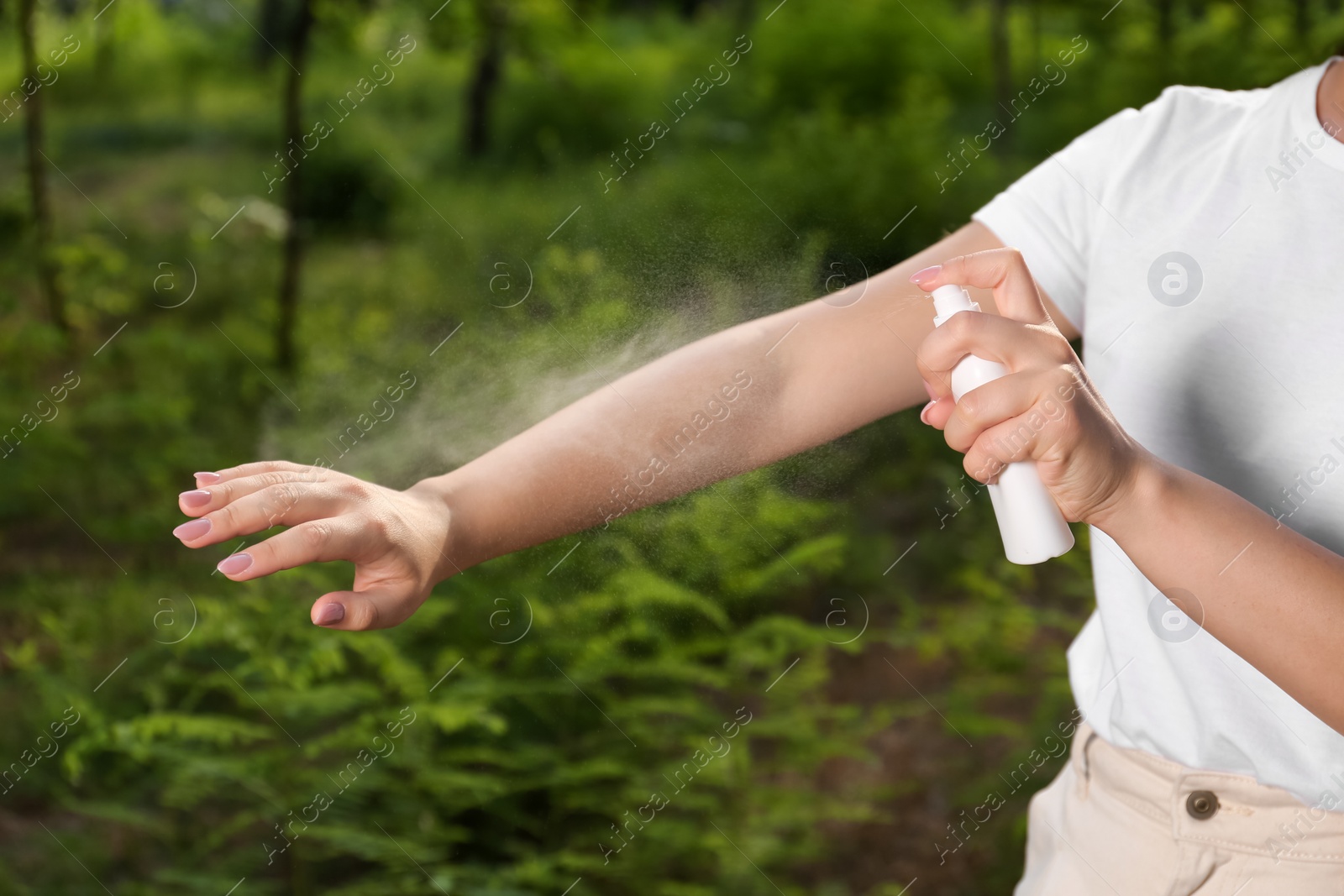Photo of Woman applying insect repellent on arm in park, closeup. Tick bites prevention