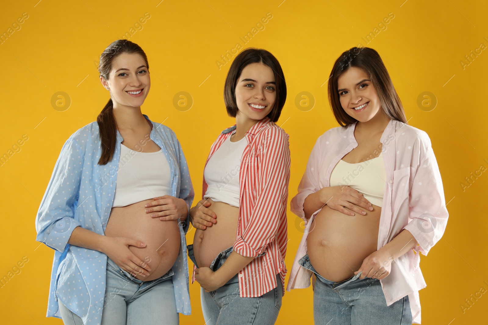 Photo of Happy young pregnant women on yellow background