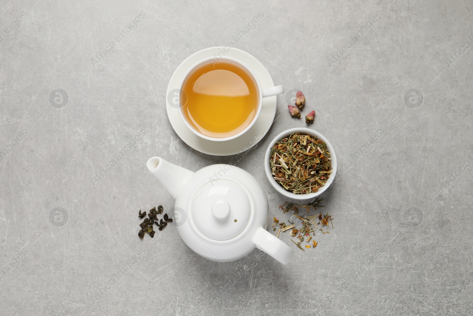 Photo of Fresh brewed tea and dry leaves on light grey background, flat lay