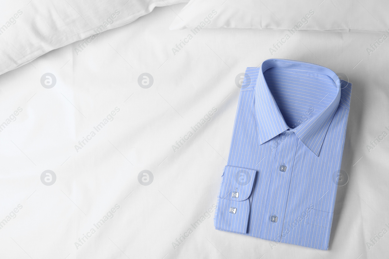 Photo of Stylish light blue shirt on bed, top view with space for text. Dry-cleaning service