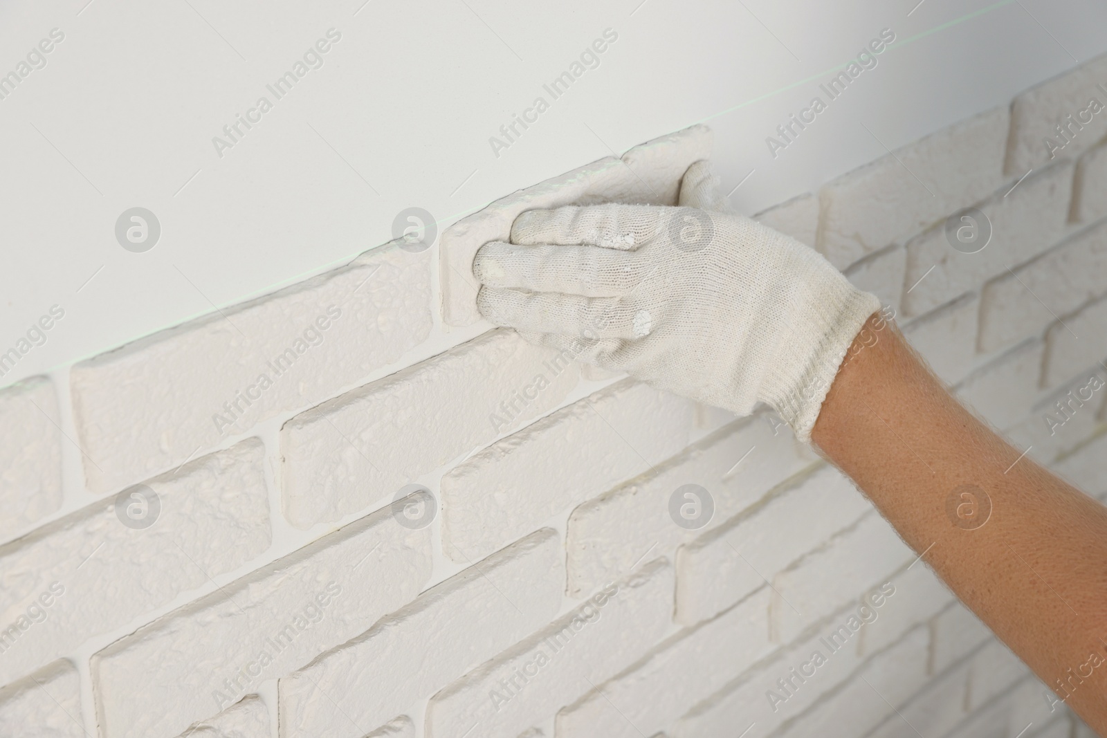 Photo of Worker installing decorative wall tiles in room, closeup