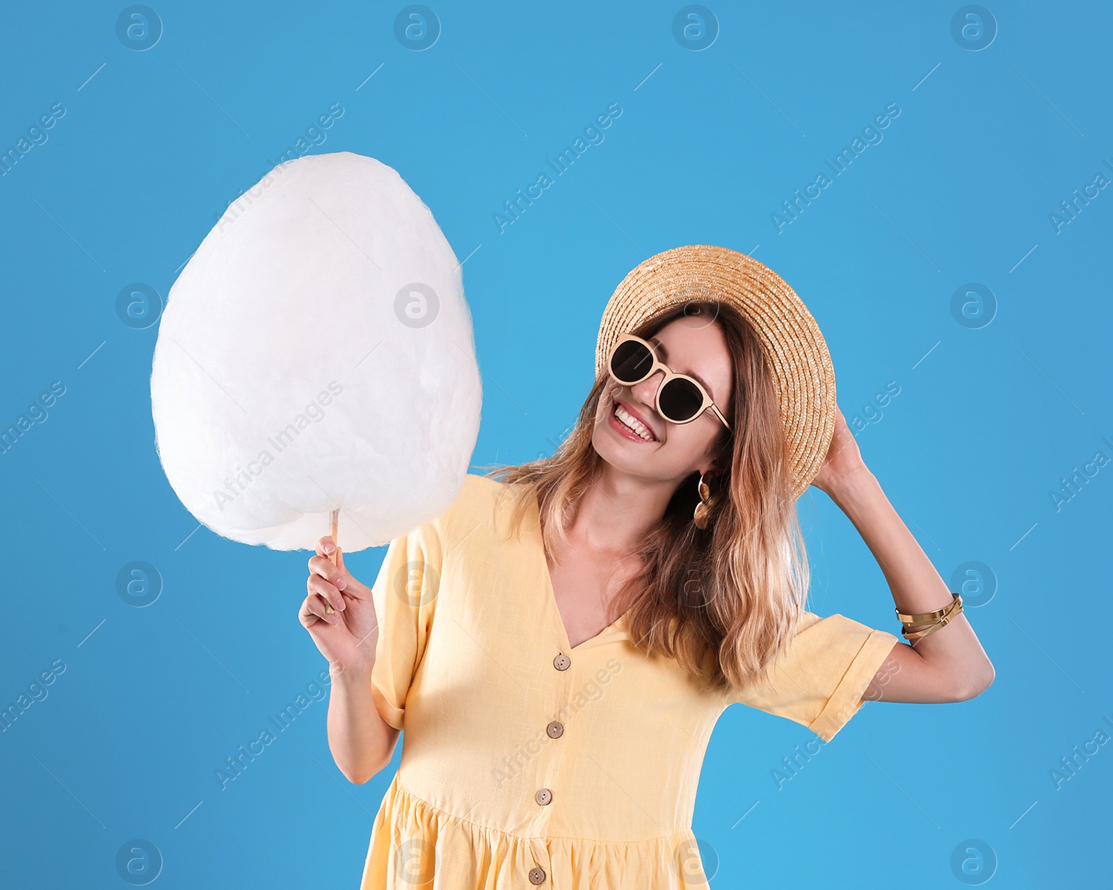 Photo of Happy young woman with cotton candy on blue background