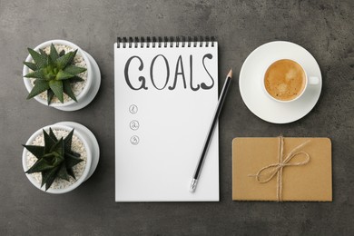 Planning concept. Empty list of goals in notebook and coffee on grey background, flat lay